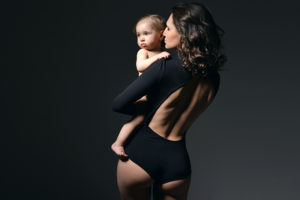Mother wearing a black leotard holding her baby