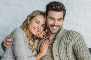 couple smiling and hugging while sitting on couch