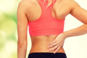 woman wearing workout gear touching her back