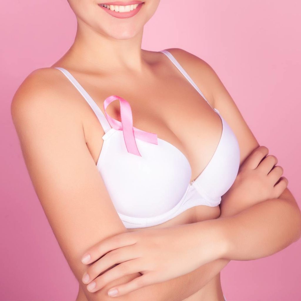 Woman in white bra with a breast cancer ribbon pin
